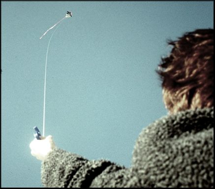 Drachenland, Fotografie, 20x20 cm, 2003 Kind, das einen Drachen mit einer Schnur in den Himmel fliegt.