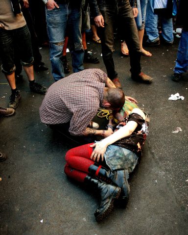 Berlin, Fotografie auf Acryl-Glas, 60x80 cm, 2007 Eine Person hilft einer am Boden liegenden Person in einer Menschenmenge.