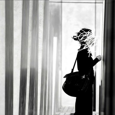 holocaust denkmal, Fotografie30x30 cm, 2008 Frau mit Handtasche steht in einem schmalen Gang, umgeben von Licht und Schatten.